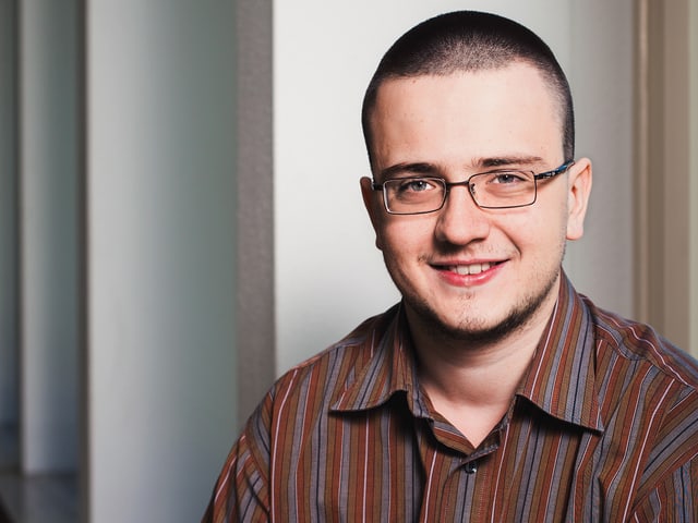 Ein junger Mann mit Brille lächelt in die Kamera. Ein junger Mann mit Brille lächelt in die Kamera.