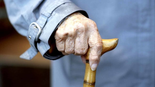 Eine alte Frau hält einen Stock in der Hand. Eine alte Frau hält einen Stock in der Hand.