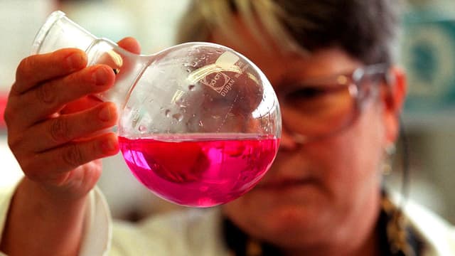 Eine Frau hält ein Reagenzglas in die Höhe. Eine Frau hält ein Reagenzglas in die Höhe.