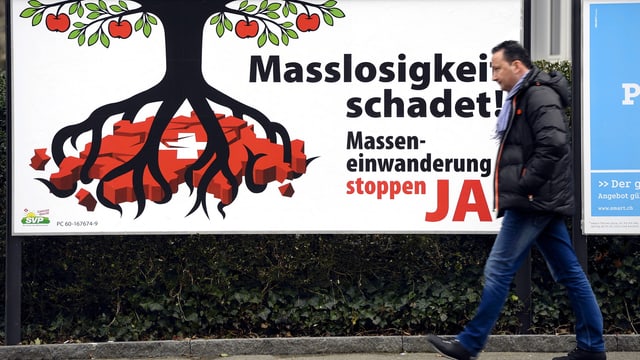 Ein Mann läuft vor einem Plakat der Masseneinwanderungsinitiative vorbei Ein Mann läuft vor einem Plakat der Masseneinwanderungsinitiative vorbei