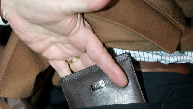 Eine Hand, die ein Portemonnaie aus einer Gesässtasche fiscfht.
