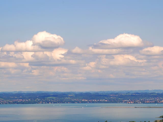 Blick von der Luft aus zu einem grossen See. Himmel blau mit Schönwetterwolken. Man sieht bis zum anderen Ufer nach Deutschland rüber.