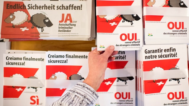 Ein Mann greift nach einem Prospekt der Befürworter der Durchsetzungs-Initiative. Ein Mann greift nach einem Prospekt der Befürworter der Durchsetzungs-Initiative.