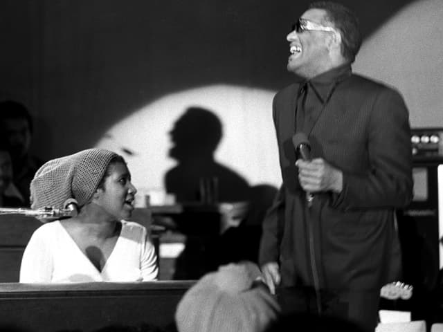 Aretha Franklin am Klavier, daneben steht Ray Charles mit Mikrofon. Aretha Franklin am Klavier, daneben steht Ray Charles mit Mikrofon.