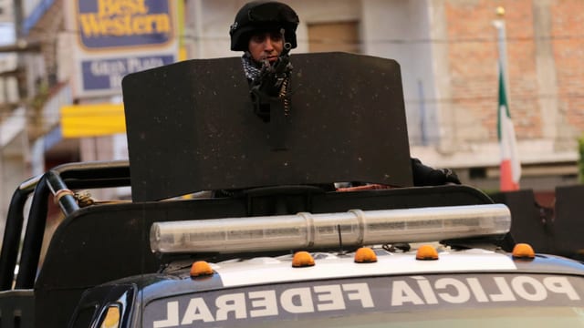 Ein Polizist hinter einem Maschinengewehr, welches auf einem Pickup befestigt ist. Ein Polizist hinter einem Maschinengewehr, welches auf einem Pickup befestigt ist.