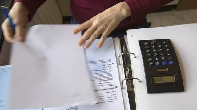 Frauenhand mit Ordner und Taschenrechner Frauenhand mit Ordner und Taschenrechner
