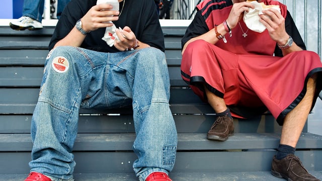 Zwei Jugendliche auf Treppe bei Fastfood-Essen. Unterschiedliche Kleiderstil. Zwei Jugendliche auf Treppe bei Fastfood-Essen. Unterschiedliche Kleiderstil.