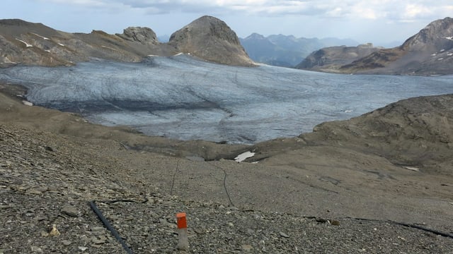Gletscher, Seile am Boden, davor ein Pfosten mit einem roten Ende Gletscher, Seile am Boden, davor ein Pfosten mit einem roten Ende