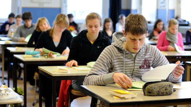 Maturanden sitzen einzeln an Tischen und lösen eine Prüfung. Maturanden sitzen einzeln an Tischen und lösen eine Prüfung.