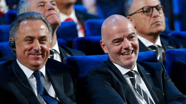 Witali Mutko und Gianni Infantino sitzen lachend nebeneinander. Witali Mutko und Gianni Infantino sitzen lachend nebeneinander.