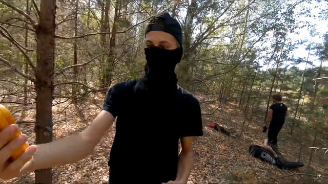 Ein junger Mann mit verhülltem Gesicht in einem Wald, er schaut auf ein gelbes Gerät. Ein junger Mann mit verhülltem Gesicht in einem Wald, er schaut auf ein gelbes Gerät.
