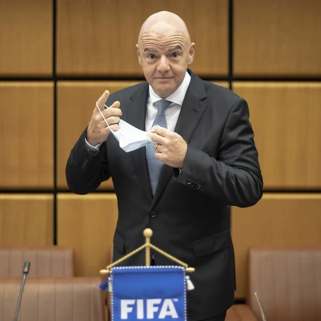 Infantino ist kurz davor eine Maske aufzusetzen und blickt in die Kamera.