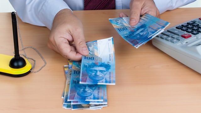 Mann legt Hunderternoten auf den Tisch Mann legt Hunderternoten auf den Tisch