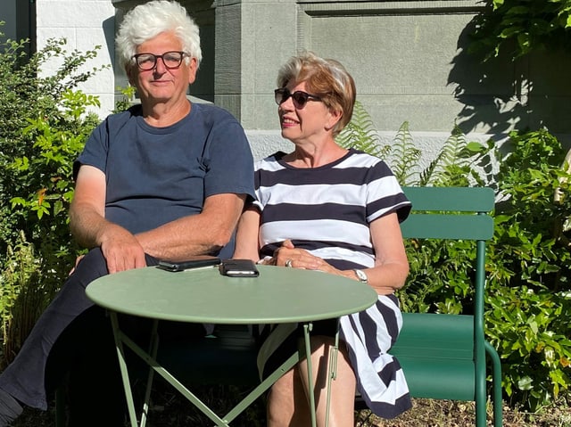 Ein Mann und eine Frau auf einer Bank vor einem Tisch Ein Mann und eine Frau auf einer Bank vor einem Tisch