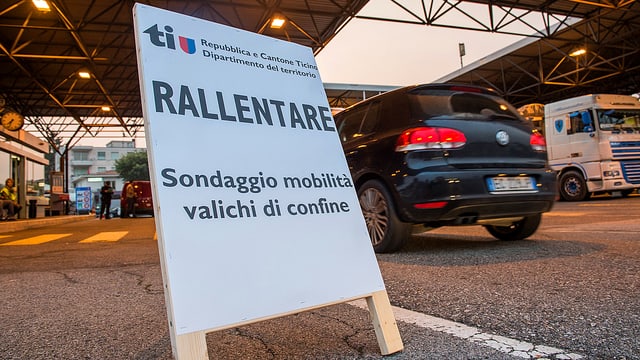 Plakat an Strassenrand stehend, Auto vorbeifahrend, im Hintergrund ist ein Schweizer Zöllner erkennbar. Plakat an Strassenrand stehend, Auto vorbeifahrend, im Hintergrund ist ein Schweizer Zöllner erkennbar.
