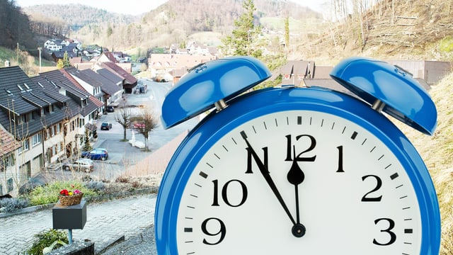 Ein Mann hält eine Uhr in die Kamera. Im Hintergrund ein Dorf Ein Mann hält eine Uhr in die Kamera. Im Hintergrund ein Dorf