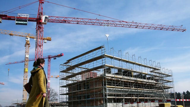 Eine Frau läuft an einer Baustelle vorbei Eine Frau läuft an einer Baustelle vorbei