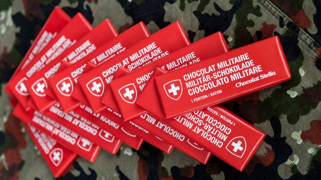 Mehrere Packungen Militärschokolade auf einer Zeltplache mit Tarnmuster. Mehrere Packungen Militärschokolade auf einer Zeltplache mit Tarnmuster.