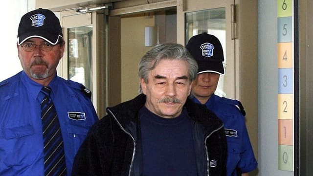 Ein Mann wird von zwei Polizisten begleitet Ein Mann wird von zwei Polizisten begleitet
