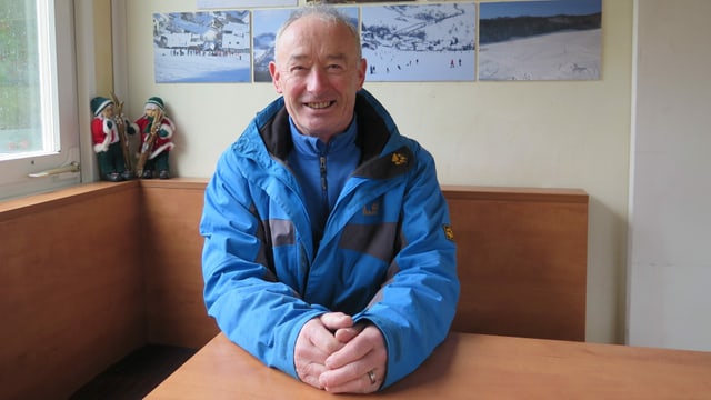 Mann in blauer Jacke sitzt am Tisch. Mann in blauer Jacke sitzt am Tisch.