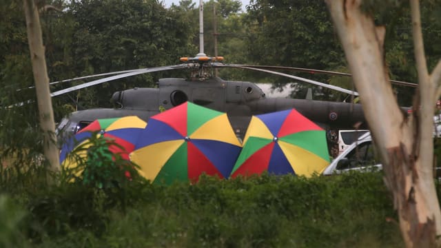 Regenschirme schirmen die letzten Buben ab, die gerettet sind und nun ins Spital geflogen werden. Regenschirme schirmen die letzten Buben ab, die gerettet sind und nun ins Spital geflogen werden.
