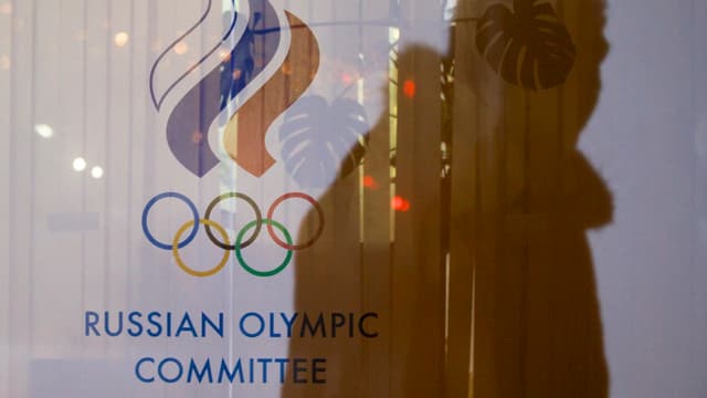 Ein Schatten eines Mannes über dem Logo des russischen olympischen Kommitees und den olympischen Ringen.