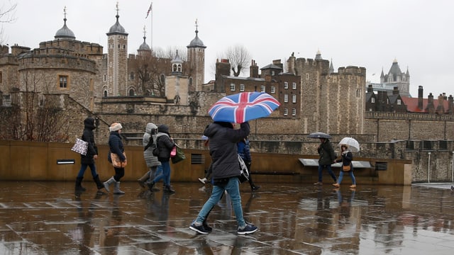 Symbolbild: Menschen vor dem London Tower, einer hat einen Regenschirm aufgespannt, der die britische Flagge zeigt. Symbolbild: Menschen vor dem London Tower, einer hat einen Regenschirm aufgespannt, der die britische Flagge zeigt.