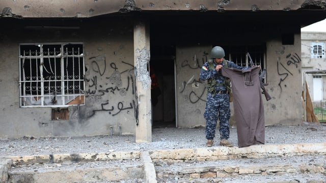 Ein kurdischer Kämpfer mit dem Kleidungsstück eines IS-Kämpfers. Ein kurdischer Kämpfer mit dem Kleidungsstück eines IS-Kämpfers.