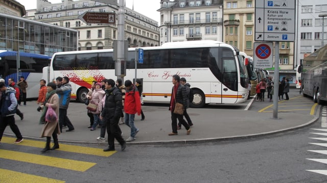 Touristen überqueren die Strasse beim Löwenplatz Luzern. Im Hintergrund sind Reisecars parkiert. Touristen überqueren die Strasse beim Löwenplatz Luzern. Im Hintergrund sind Reisecars parkiert.