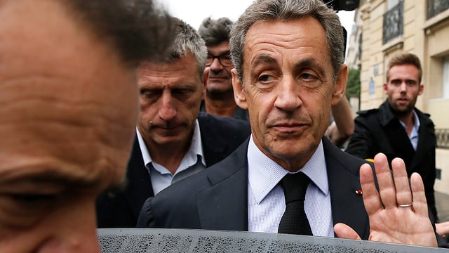 Nicola Sarkozy umgeben von Männern grüsst mit der offenen Handlfäche Journalisten Nicola Sarkozy umgeben von Männern grüsst mit der offenen Handlfäche Journalisten
