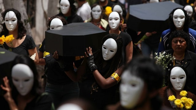 Frauen mit weissen Masken und schwarz verhüllt tragen Särge Frauen mit weissen Masken und schwarz verhüllt tragen Särge