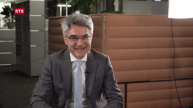 Mario Cavigelli ri en la camera en il zuler dal biro dal departement d'infrastructura, energia e mobilitad. Davos el in gond sort da sofa e cumpartement per duas persunas. Mario Cavigelli ri en la camera en il zuler dal biro dal departement d'infrastructura, energia e mobilitad. Davos el in gond sort da sofa e cumpartement per duas persunas.