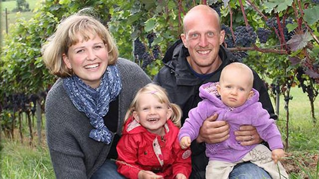 Familie mit zwei Kindern vor Rebstöcken. Familie mit zwei Kindern vor Rebstöcken.