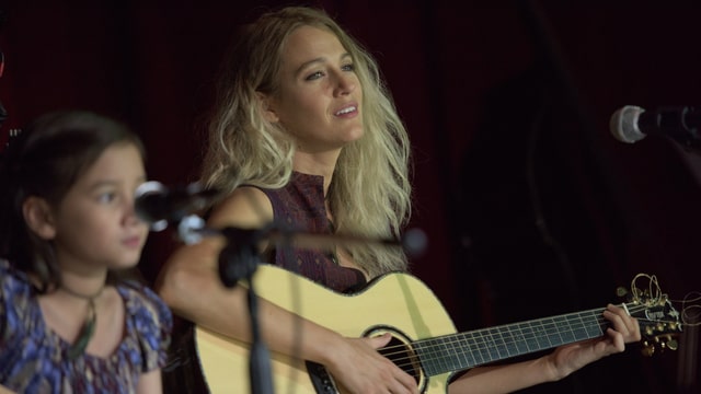 Blake Lively singend, mit blonden Haaren und Gitarre. Blake Lively singend, mit blonden Haaren und Gitarre.