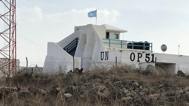 Weissgestrichener Betonbunker. Darauf weht UNO-Flagge. Er ist mit OP 51 angeschrieben. Weissgestrichener Betonbunker. Darauf weht UNO-Flagge. Er ist mit OP 51 angeschrieben.