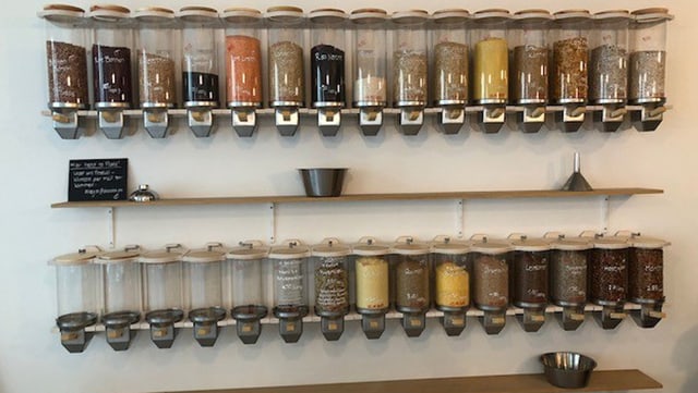 Mit Esswahren gefüllte Glasbehälter an einer Wand Mit Esswahren gefüllte Glasbehälter an einer Wand