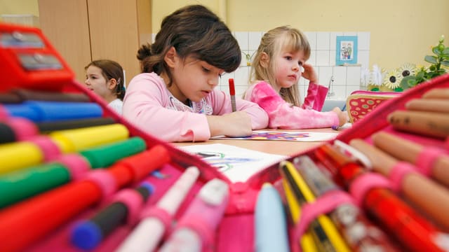 Junge Schülerinnen malen an einem Tisch Junge Schülerinnen malen an einem Tisch