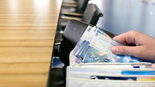 Sitzungszimmer, im Vordergrund eine Hand, die Geld ins Portemonnaie steckt... Sitzungszimmer, im Vordergrund eine Hand, die Geld ins Portemonnaie steckt...