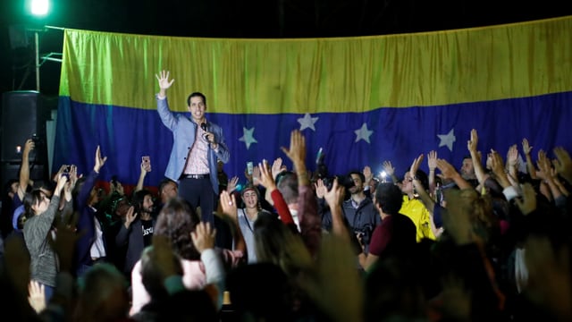 Guaido on a stage, people cheer him up.