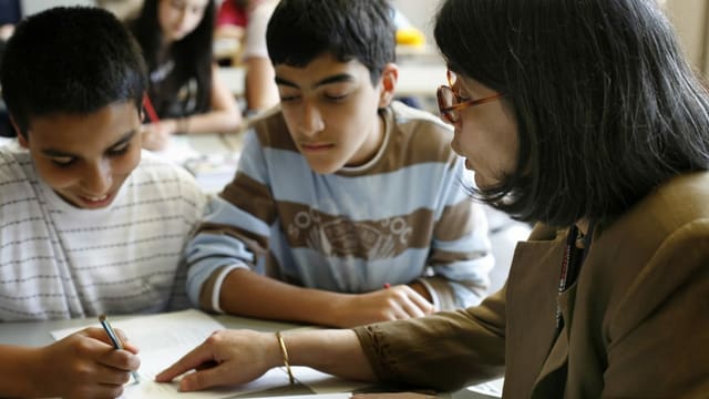 Lehrerin gibt zwei Schülern Nachhilfe Lehrerin gibt zwei Schülern Nachhilfe