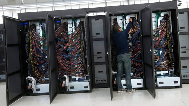 Drei offene Schränke voller Kabel, die mehrere Rechner miteinander verbinden. Drei offene Schränke voller Kabel, die mehrere Rechner miteinander verbinden.