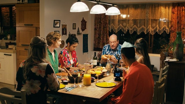 Filmausschnitt: 6 Menschen sitzen um einen Tischen und Essen. Filmausschnitt: 6 Menschen sitzen um einen Tischen und Essen.