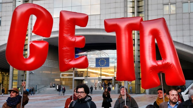Personen halten die roten Letter C E T A hoch. Personen halten die roten Letter C E T A hoch.