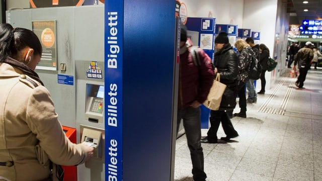 Personen kaufen ihr Bahnbillett an einem Automaten Personen kaufen ihr Bahnbillett an einem Automaten