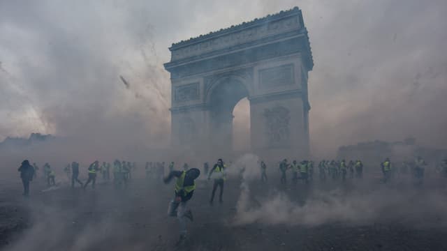 Gilets Jaunes vor dem Arc de Triomphe umgeben von Rauch Gilets Jaunes vor dem Arc de Triomphe umgeben von Rauch