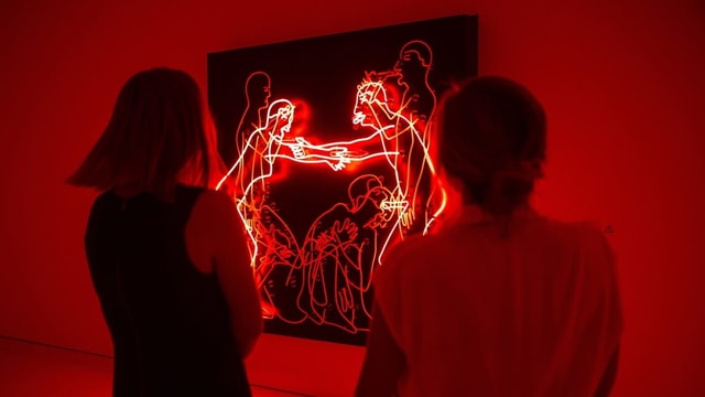 Besuchen schauen sich eine Lichtinstallation von Bruce Nauman an. Sie ist rot und zeigt ein Paar beim Sex. Besuchen schauen sich eine Lichtinstallation von Bruce Nauman an. Sie ist rot und zeigt ein Paar beim Sex.