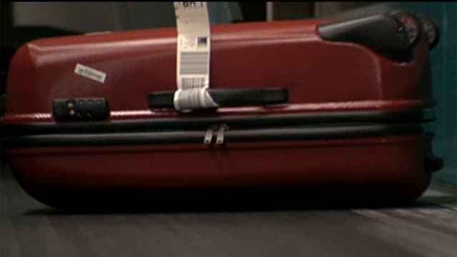 Roter Koffer auf einem Flughafen-Fliessband. Roter Koffer auf einem Flughafen-Fliessband.