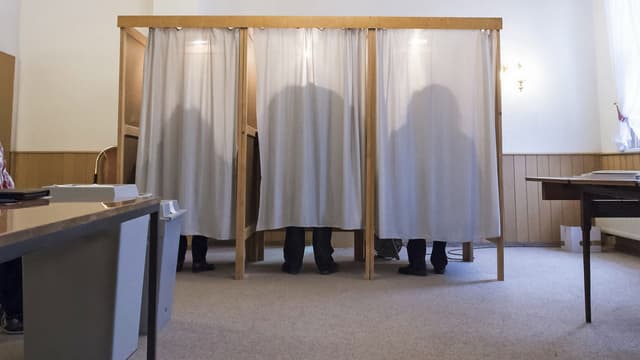 Sihouetten von drei Menschen in drei Wahlkabinen Sihouetten von drei Menschen in drei Wahlkabinen