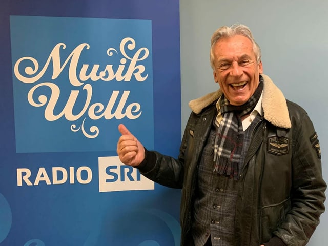 Pepe Lienhard steht vor Musikwelle Logo. Pepe Lienhard steht vor Musikwelle Logo.