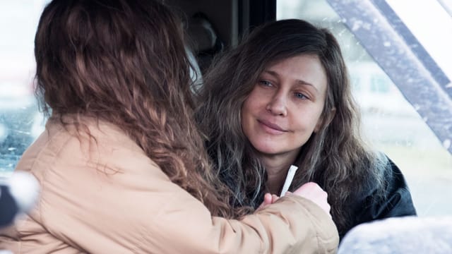 Eine Frau sitzt in einem Auto. Neben ihr ein Mädchen, das man nur von hinten sieht. Die Frau reicht dem Mädchen einen Joint. Eine Frau sitzt in einem Auto. Neben ihr ein Mädchen, das man nur von hinten sieht. Die Frau reicht dem Mädchen einen Joint.